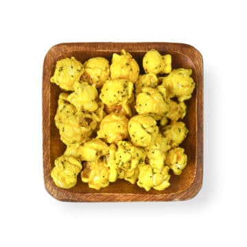 Popinsanity Lemon Poppy gourmet popcorn, featuring golden, crunchy clusters coated in a tangy lemon glaze and poppy seeds, ready to be enjoyed, in a simple wooden bowl.