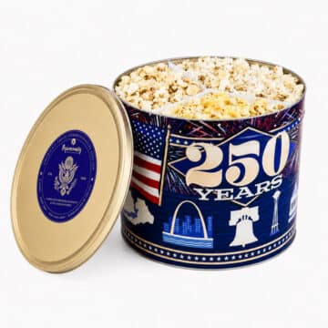 Popinsanity 250 Years America commemorative edition popcorn tin with gold lid open showcasing three gourmet flavors.